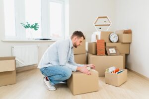 young man packing cardboard boxes home